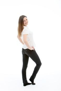 Smiling young woman with lovely figure dressed in close fitting black jeans posing and looking back over her shoulder at the camera isolated on white
