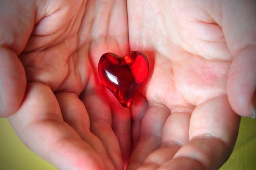 Glowing red heart hold on the palm of one's hands