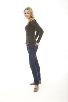 smiling woman wearing a grey top standing with hands on her back pocket on a white background