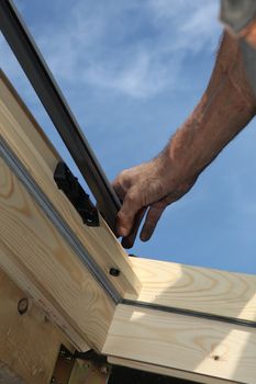 Close-up shot of carpenter who takes measures with blue sky as background