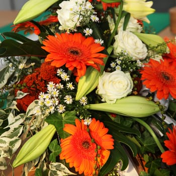 Colourful orangey-red Gerbera flowers in a mixed floral decoration with roses and lilies