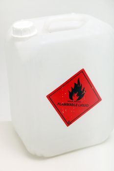 White plastic container with a red flammable hazard label on the outside