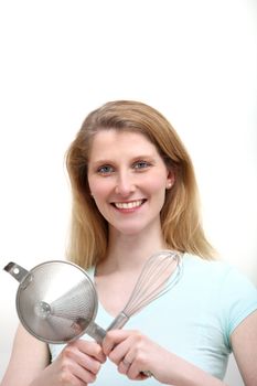 Attractive woman with kitchen utensils on white background