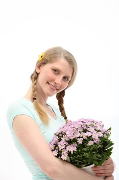 Attractive blonde woman smiling in appreciation and thanks as she clutches a gift of a bouquet of decorative pink flowesr