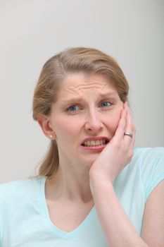 Woman with toothache holding her cheek and struggles with pain