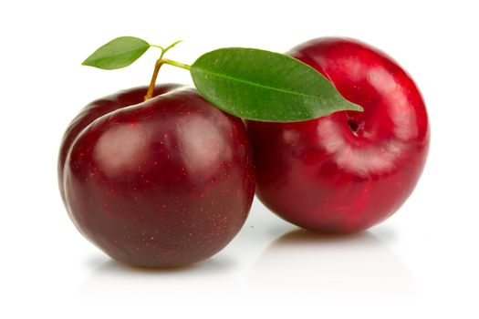 Ripe plums fruits with green leaves isolated on white background