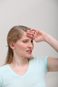 Blonde woman in pain holding her head