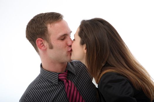 Young affectionate couple in business attire enjoying a spontaneous kiss isolated on white