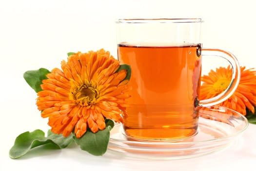 a glass of marigold tea and calendula flowers on a bright background