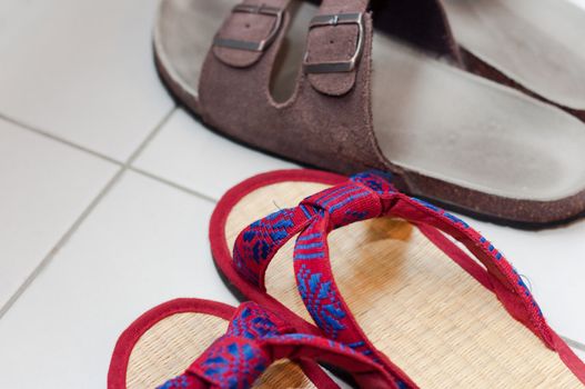 Closeup of vietnamese and european slippers on white floor