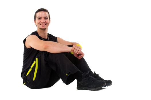 Young male fitness teacher sitting on floor