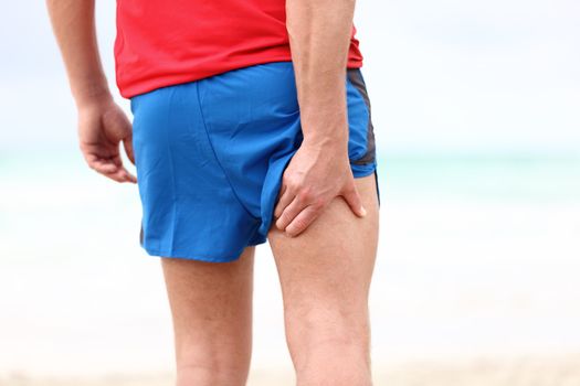 Running sports injury. Pulled muscle, muscle strain or muscle cramp in back thigh leg of man running outdoors.