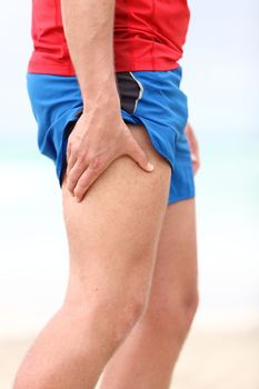 Muscle sports injury. Running muscle strain injury in thigh. Closeup of runner touching leg in muscle pain.