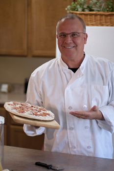 chef with frozen pizza in kitchen presenting