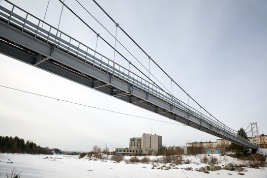 Suspension Bridge over the River Niva. Winter landscape.