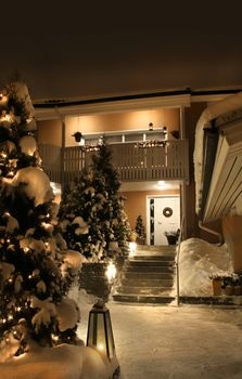 Snowy entrance of house in idyllic Christmas time evening light