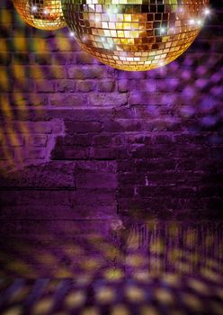 Golden mirror balls reflect lights on dramatic dark disco brick wall