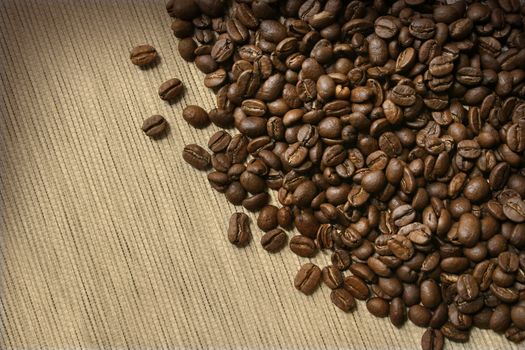 Roasted dark brown coffee beans on burlap background