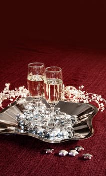 Two sparkling champagne glasses on red decorated backround