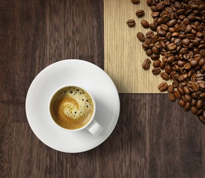 Cup of fresh espresso and roasted coffee beans on dark wooden background