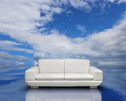 White sofa and silver frames on reflective cloudscape reflection surface