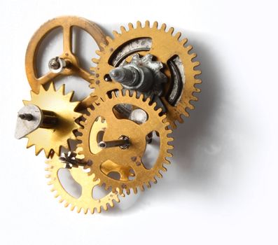 Old clockwork mechanism with brass metal cogs on white background