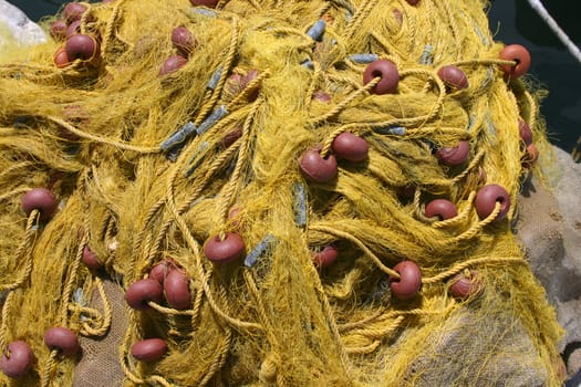 Yellow fishing net with floats gathered on pier