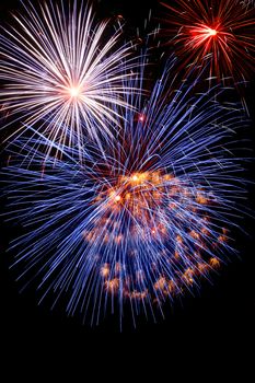 Blue white and red fireworks on dark night sky background