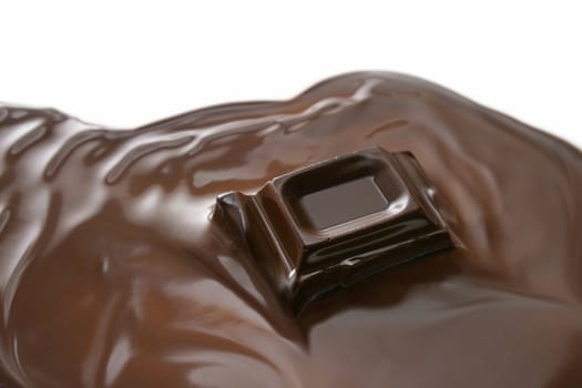 Melting piece of dark chocolate on white background