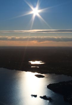 Midnight sun shining over forest and reflective lake scenery