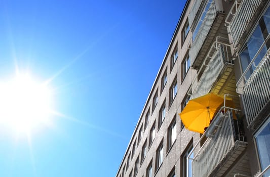 Yellow sun umrella on balcony in hot summer day burning