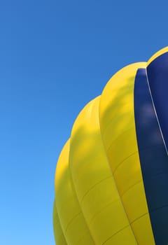 Yellow and blue hot air balloon on bright blue sky background