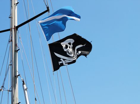 Black and white pirate skull and bones flag waving on mast