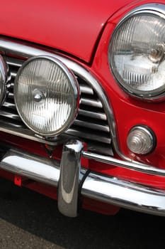Chromed grille , bumper and twin headlamps of classic red rally car