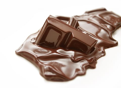 Melting piece of dark chocolate on white background