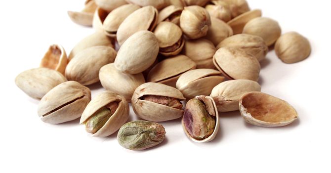 Dried and salted pistachio nuts on white background