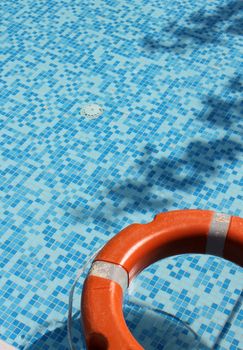 Life saver buoy ring floating in turquoise swimming pool