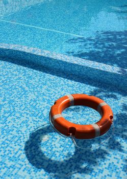 Life saver buoy ring floating in turquoise swimming pool