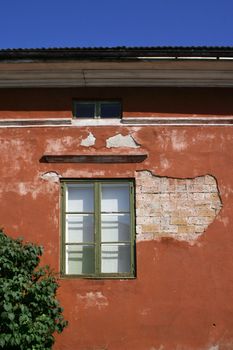 Red old stone house with decayded plaster wall