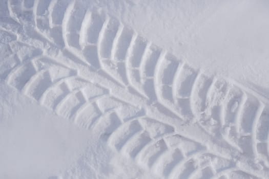 Diagonal track of car tire in pure white snow