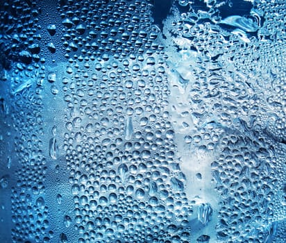 Refreshing water drops on blue transparent surface