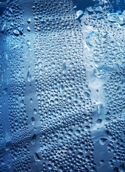 Refreshing water drops on blue transparent surface