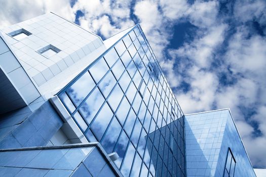windows of skyscraper with reflections on a background cloudy sky