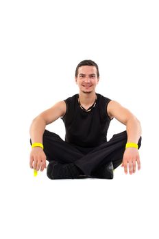 Young male fitness teacher sitting on floor