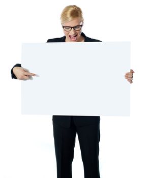 Successful business female pointing at white blank billboard. Looking down