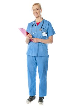 Full length view of senior female doctor holding reports, smiling at camera