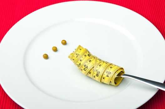 Plate with three peas and a measuring tape around a fork.