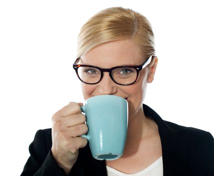Attractive corporate female drinking coffee, holding mug