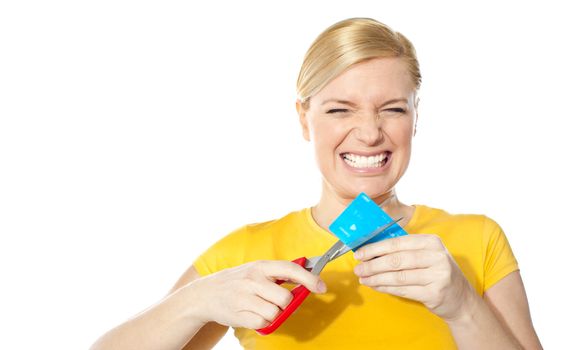 Woman grinding teeth while cutting her credit card isolated over white