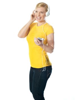 Pretty woman holding music player with headphones attached. Enjoying music